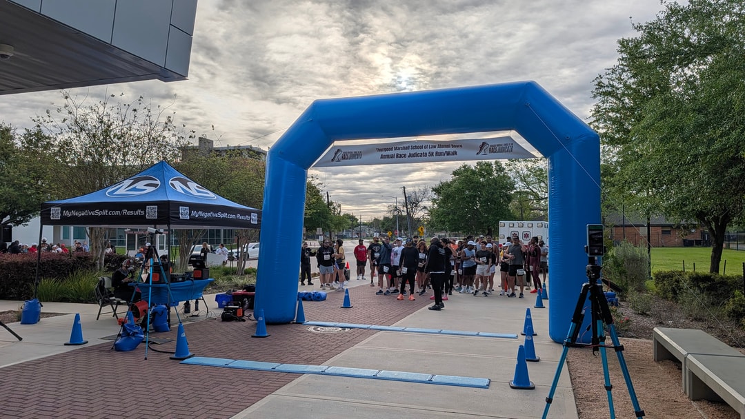 Inflatable arch, timing mats, cones, and camera tripods set up before the start of a 5K