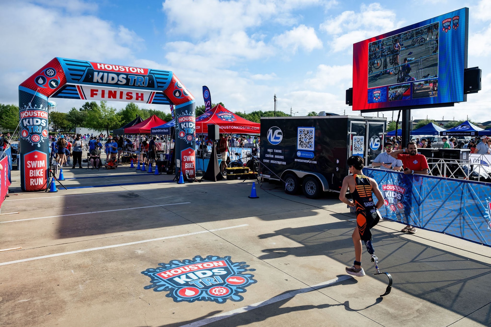 The LED screen showing live finish line video beside the Houston Kids Tri finish arch